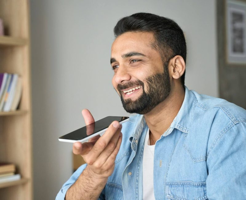 young-indian-man-speaking-to-voice-assistant-using-smartphone-.jpg young-indian-man-speaking-to-voice-assistant-using-smartphone-.jpg